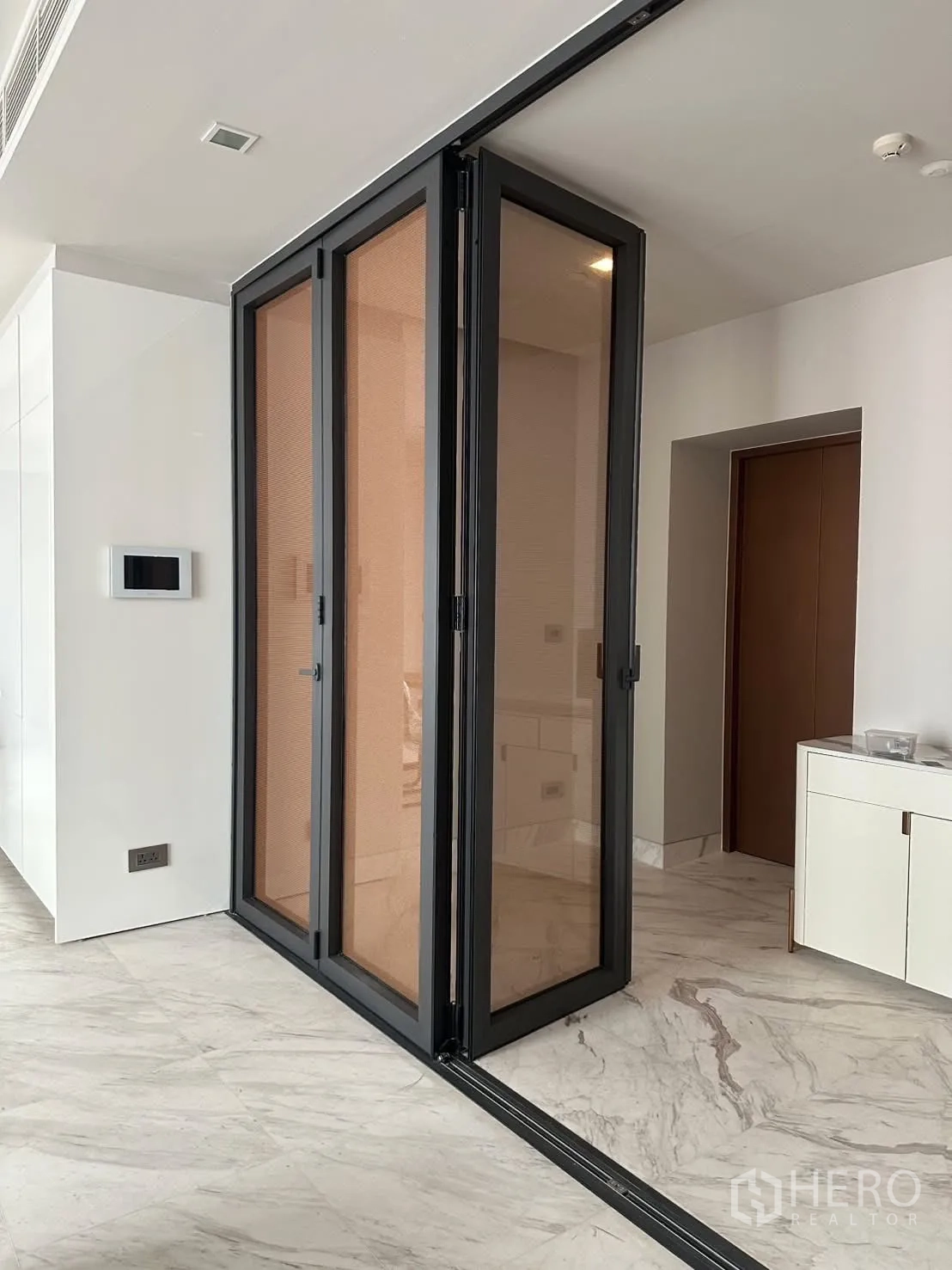 Condominium for rent or sale in Watthana, Bangkok - Sliding glass room divider with black frames on marble flooring.