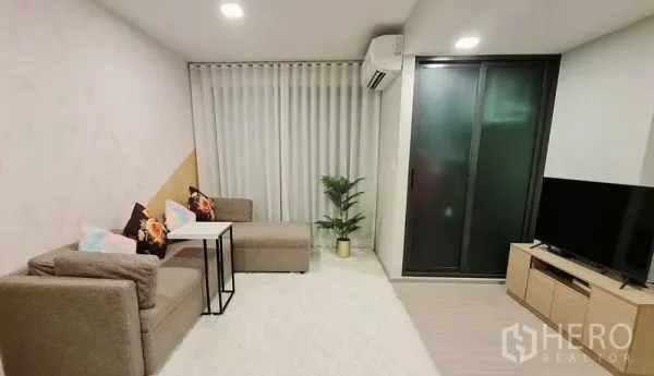 Condominium for rent in Phra Khanong, Bangkok - Cozy living room with sofa set, TV console, sliding glass door, and curtains.