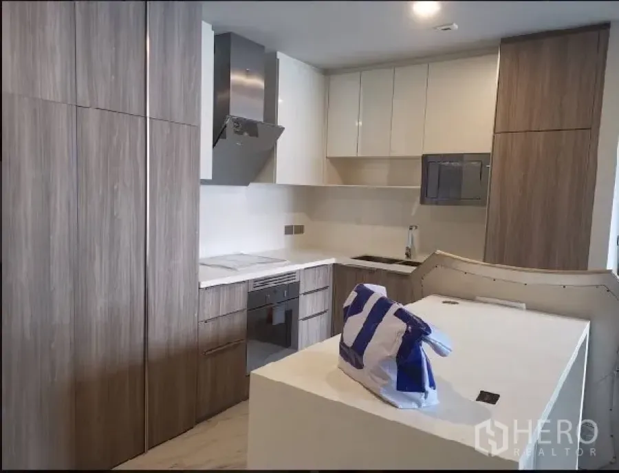 คอนโด ให้เช่าในWatthana, Bangkok - ครัวคอนโดสไตล์โมเดิร์น ตู้ลายไม้ เตาอบบิวท์อิน เครื่องดูดควัน และเคาน์เตอร์ไอส์แลนด์สีขาว