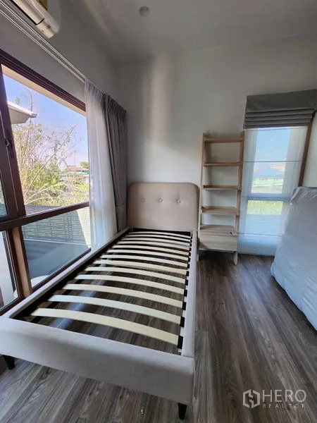 Detached House for rent in Bang Kapi, Bangkok - Secondary bedroom with single bed frame, shelves and corner windows.