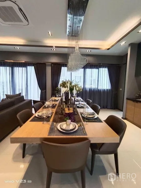 Detached House for sale in Wang Thonglang, Bangkok - Elegant dining room with long wooden table set for eight and a crystal chandelier.