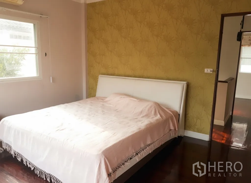 บ้าน ให้เช่าในLat Krabang, Bangkok - ห้องนอนใหญ่ ผนังลายวอลเปเปอร์สีเหลือง หน้าต่างบานใหญ่ และพื้นไม้เงางาม