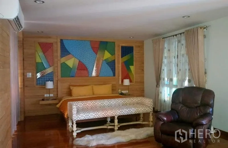 Home Office for sale in Phasi Charoen, Bangkok - Spacious bedroom with colorful wall art, large bed, window drapes and a recliner chair.