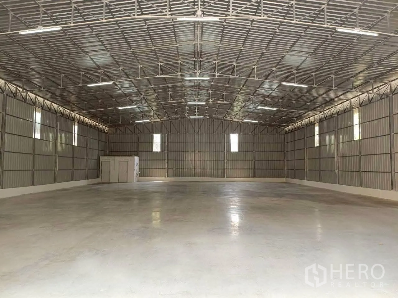 Warehouse for rent in Prawet, Bangkok - Wide warehouse interior with steel roof trusses, high clearance, lighting and concrete floor.