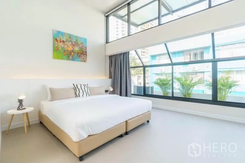 ทาวน์เฮาส์ ให้เช่าในKhlong Toei, Bangkok - ห้องนอนสว่างโปร่ง เพดานสูง ผนังหน้าต่างยาว และกระบะต้นไม้ริมระเบียง