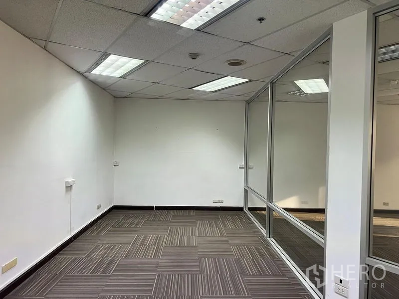 Office Space for rent in Khlong Toei, Bangkok - Glass-partitioned meeting or manager’s room with fluorescent lighting and striped carpet.