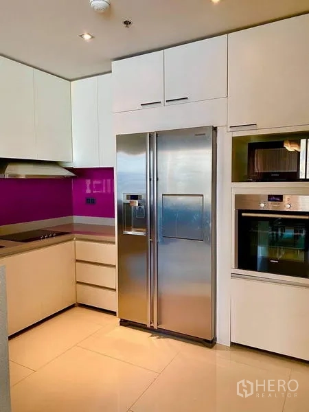 คอนโด ให้เช่า - ครัวรูปตัวแอล ตู้สีขาว ตู้เย็นสแตนเลส และเตาอบบิวท์อิน