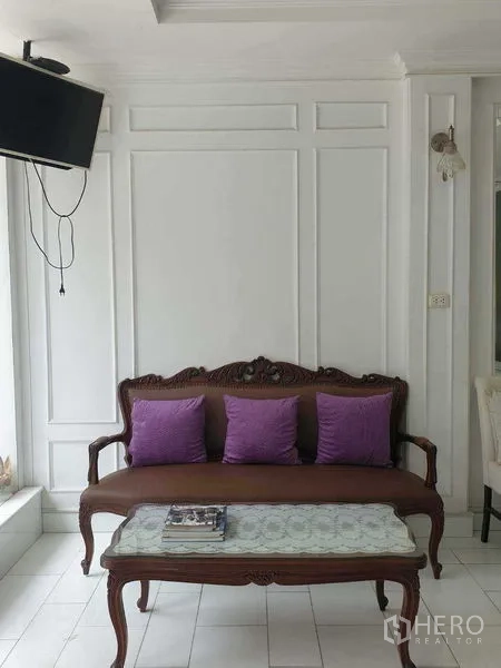 零售空间 出租在Huai Khwang, Bangkok - 复古木沙发配紫色靠垫，墙装电视位于前厅。