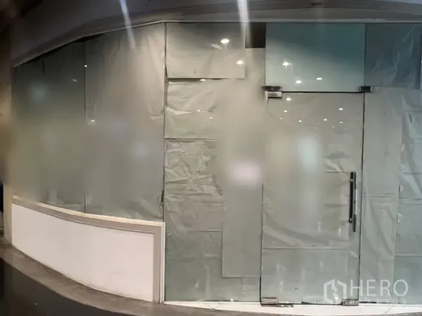 พื้นที่ขายปลีก ให้เช่าในWatthana, Bangkok - หน้าร้านกระจกบานโค้ง ปิดด้วยกระดาษ อยู่ในโถงศูนย์การค้าทันสมัย