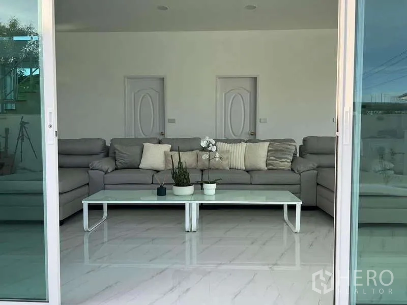 บ้าน ให้เช่าในLat Krabang, Bangkok - ประตูกระจกบานเลื่อนเปิดสู่ห้องนั่งเล่น โซฟาสีเทาและโต๊ะกลางสีขาว