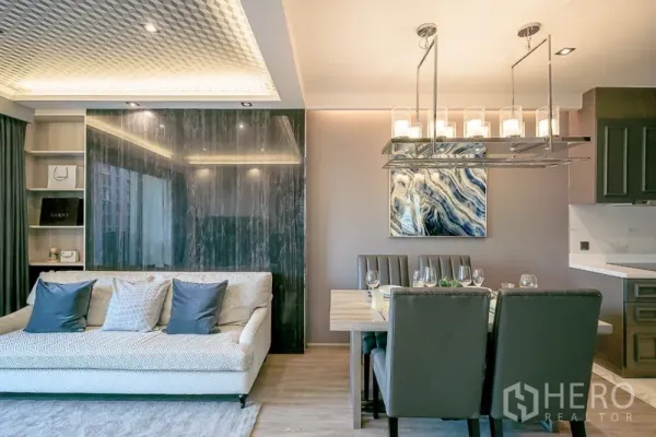 Condominium for rent in Watthana, Bangkok - Elegant dining space with chandelier beside a sofa and glossy marble feature wall.