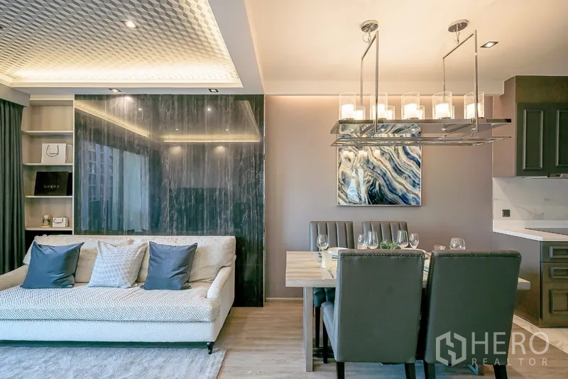 Condominium for rent in Watthana, Bangkok - Elegant dining space with chandelier beside a sofa and glossy marble feature wall.