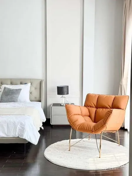 独立式住宅 出租或出售在Bang Phli, Samut Prakan - 卧室温馨一角，橙色休闲椅置于圆形地毯上，旁有床与床头柜。