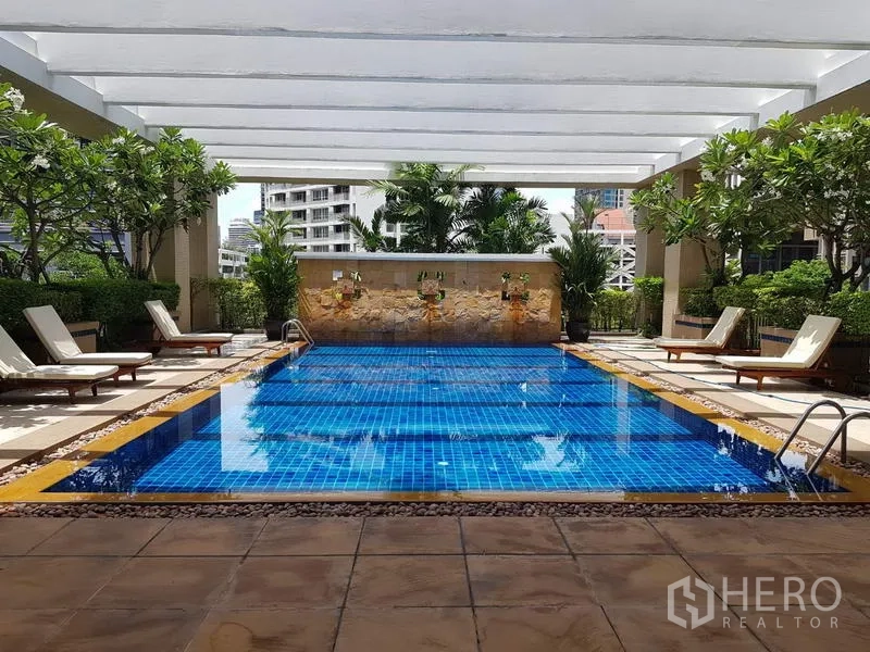 公寓 出租在Pathum Wan, Bangkok - 公寓游泳池，蓝色马赛克池底，躺椅与绿化景观。