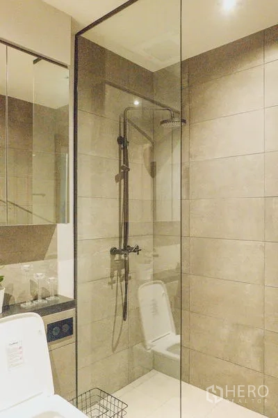 Condominium for rent in Watthana, Bangkok - Glass-enclosed rainfall shower with beige wall tiles.