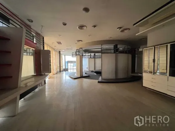 零售空间 出租 - 宽敞零售展厅，带圆形展示结构、内置货架、木地板与落地玻璃窗