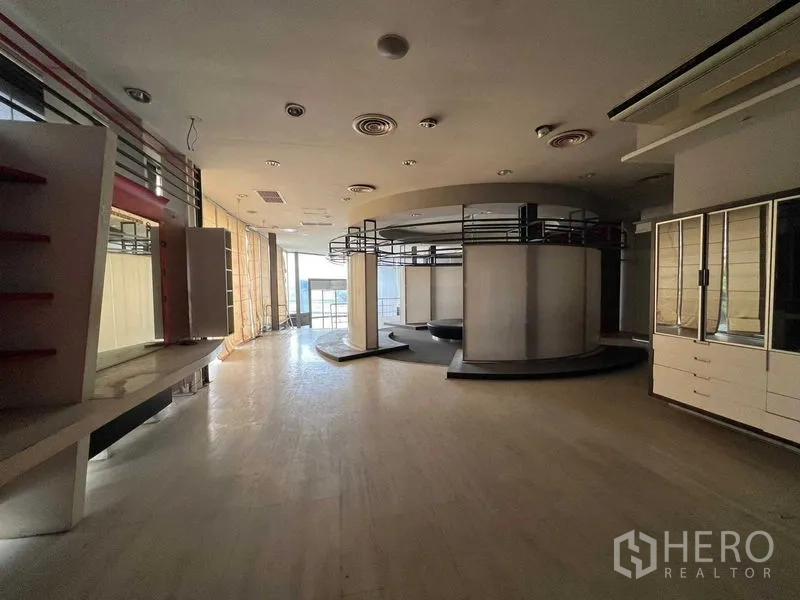 零售空间 出租 - 宽敞零售展厅，带圆形展示结构、内置货架、木地板与落地玻璃窗