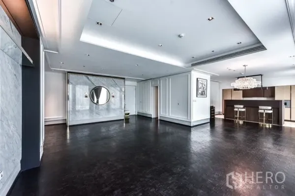 公寓 出租在Bang Rak, Bangkok - 宽敞的客餐厅，深色木地板、石材特色墙与水晶吊灯，旁有厨房吧台。