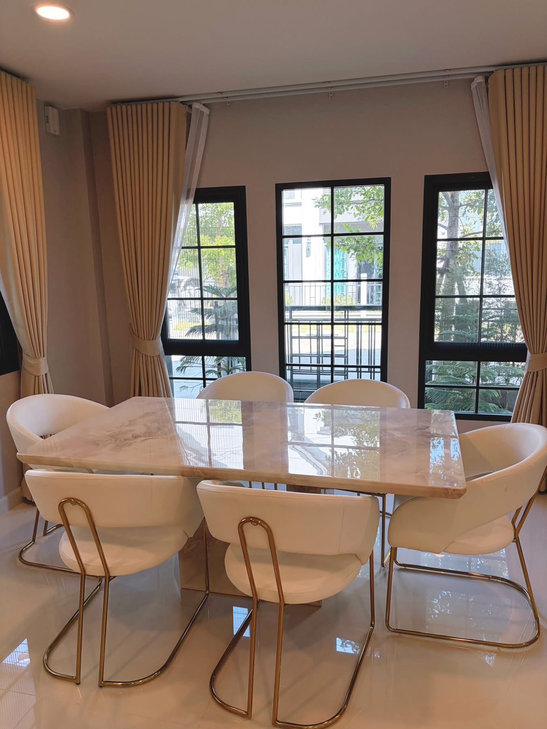 独立式住宅 出租在Bang Phli, Samut Prakan - 餐区设大理石餐桌与六把白椅，黑框落地窗采光佳。
