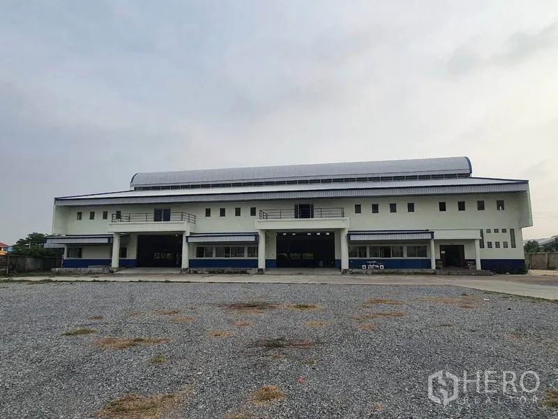 工厂 出租在Bang Bua Thong, Nonthaburi - 对称的厂房正面，前方宽阔车道与碎石场。