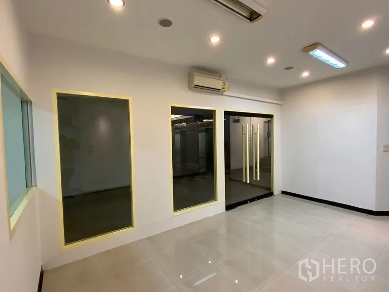 Office Space for rent in Watthana, Bangkok - Main office room with double glass doors, large windows, air conditioner, and ceiling downlights.
