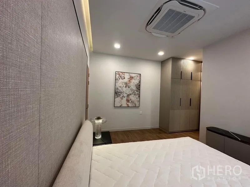 Detached House for rent in Samut Prakan - Alternate angle of bedroom showing built-in wardrobes and wall art.