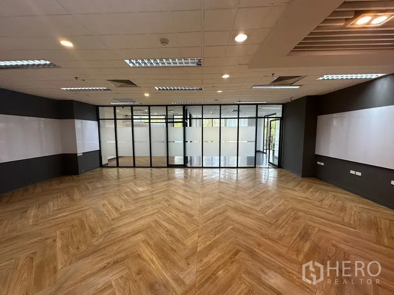 Office Space for rent - Spacious office with herringbone wood flooring, glass-partitioned meeting rooms and recessed lighting.