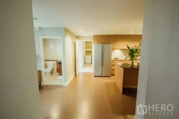 บ้าน ให้เช่าในKhlong Toei, Bangkok - มุมมองจากโถงทางเดินเข้าสู่ครัว มีตู้เย็นทรงสูง ไอแลนด์ และห้องน้ำแขกข้างๆ.