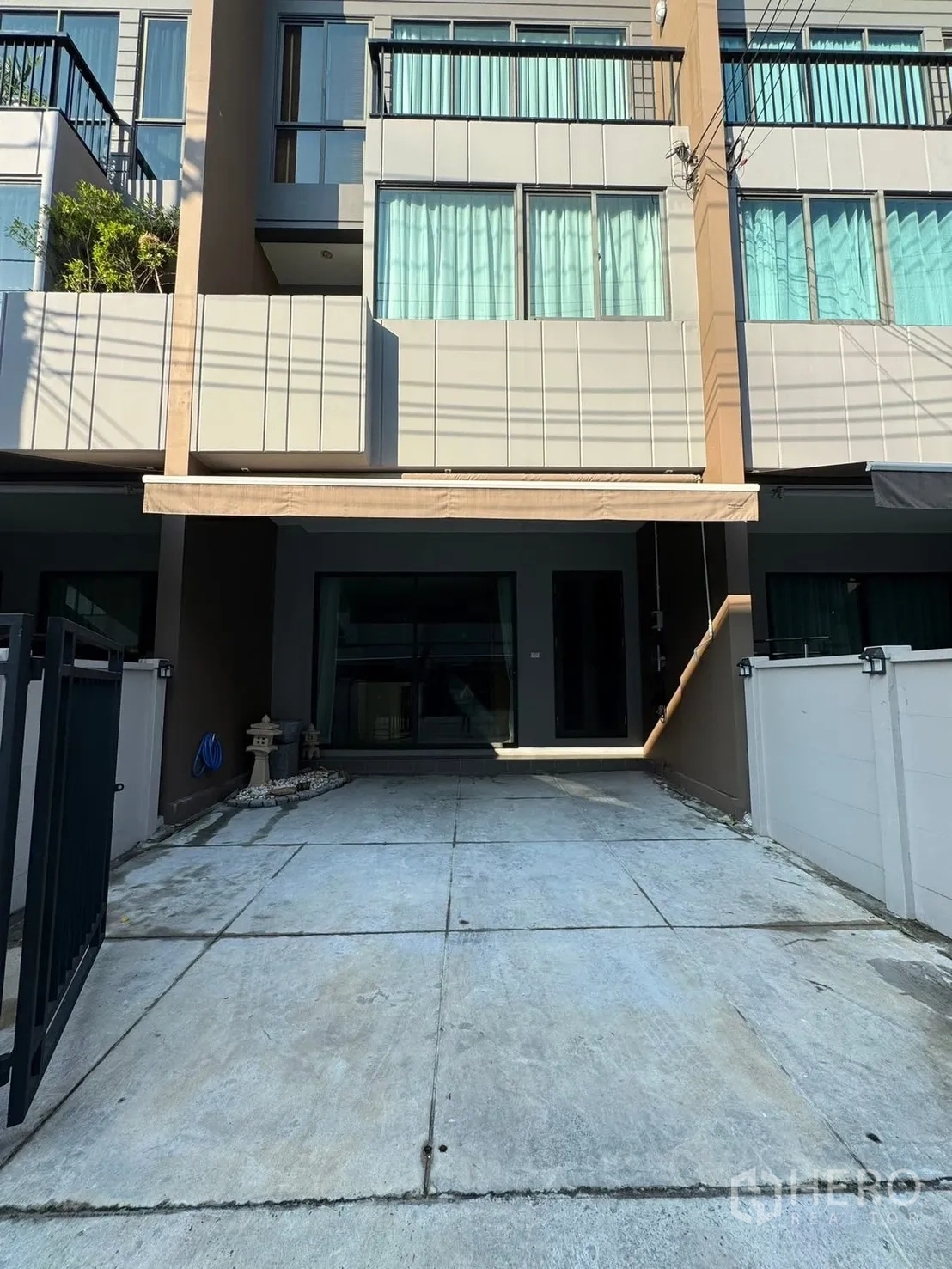 Townhouse for rent in Saphan Sung, Bangkok - Modern three-storey townhouse facade with gated driveway parking.