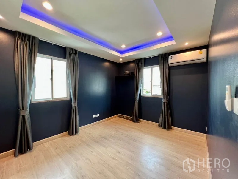 บ้าน ขายในBang Sao Thong, Samut Prakan - ห้องนอนกว้างผนังสีน้ำเงินเข้ม ไฟซ่อนฝ้า พื้นไม้ และเครื่องปรับอากาศ