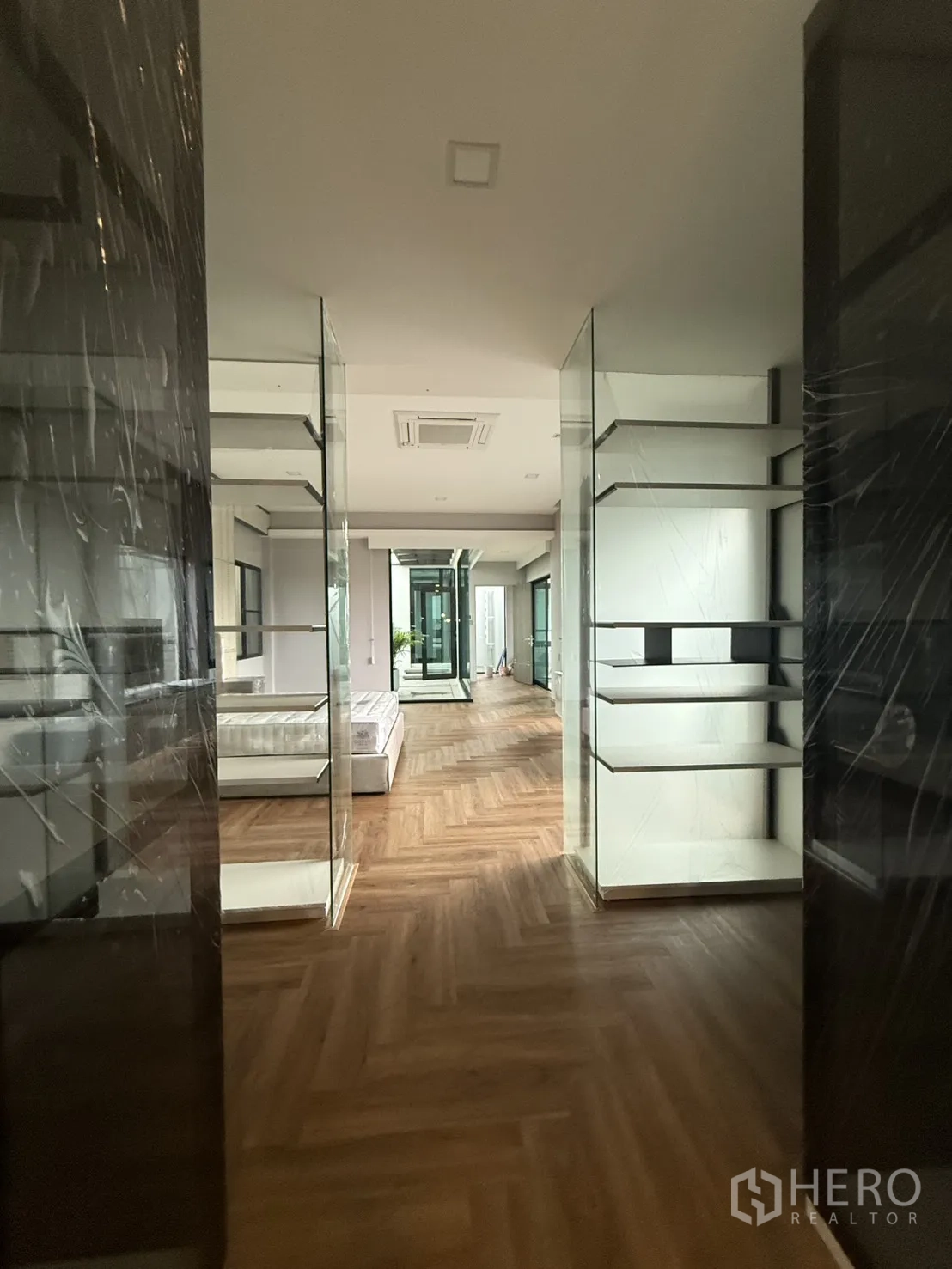 Detached House for rent in Saphan Sung, Bangkok - Expansive bedroom with tufted bed, herringbone floors and corridor to the atrium.