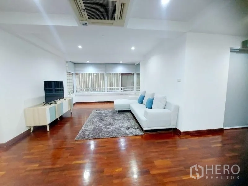 คอนโด ให้เช่าในWatthana, Bangkok - ห้องนั่งเล่น โซฟาเข้ามุมสีขาว พรม ชั้นวางทีวี แอร์แขวน และหน้าต่างบานกว้าง