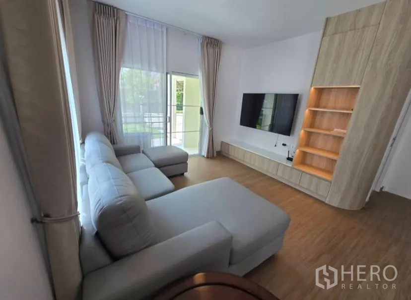 Detached House for rent in Bang Phli, Samut Prakan - Bright lounge with sliding glass doors to the garden and a TV wall unit.