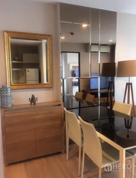 Condominium for rent in Sathon, Bangkok - Dining corner with mirrored wall, black glass table, sideboard and contemporary floor lamps.