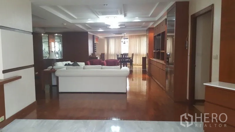 คอนโด ให้เช่าในKhlong Toei, Bangkok - พื้นที่นั่งเล่นกว้าง โซฟาสีขาว ตู้บิวท์อินสำหรับทีวี และผ้าม่านสูงจรดพื้น