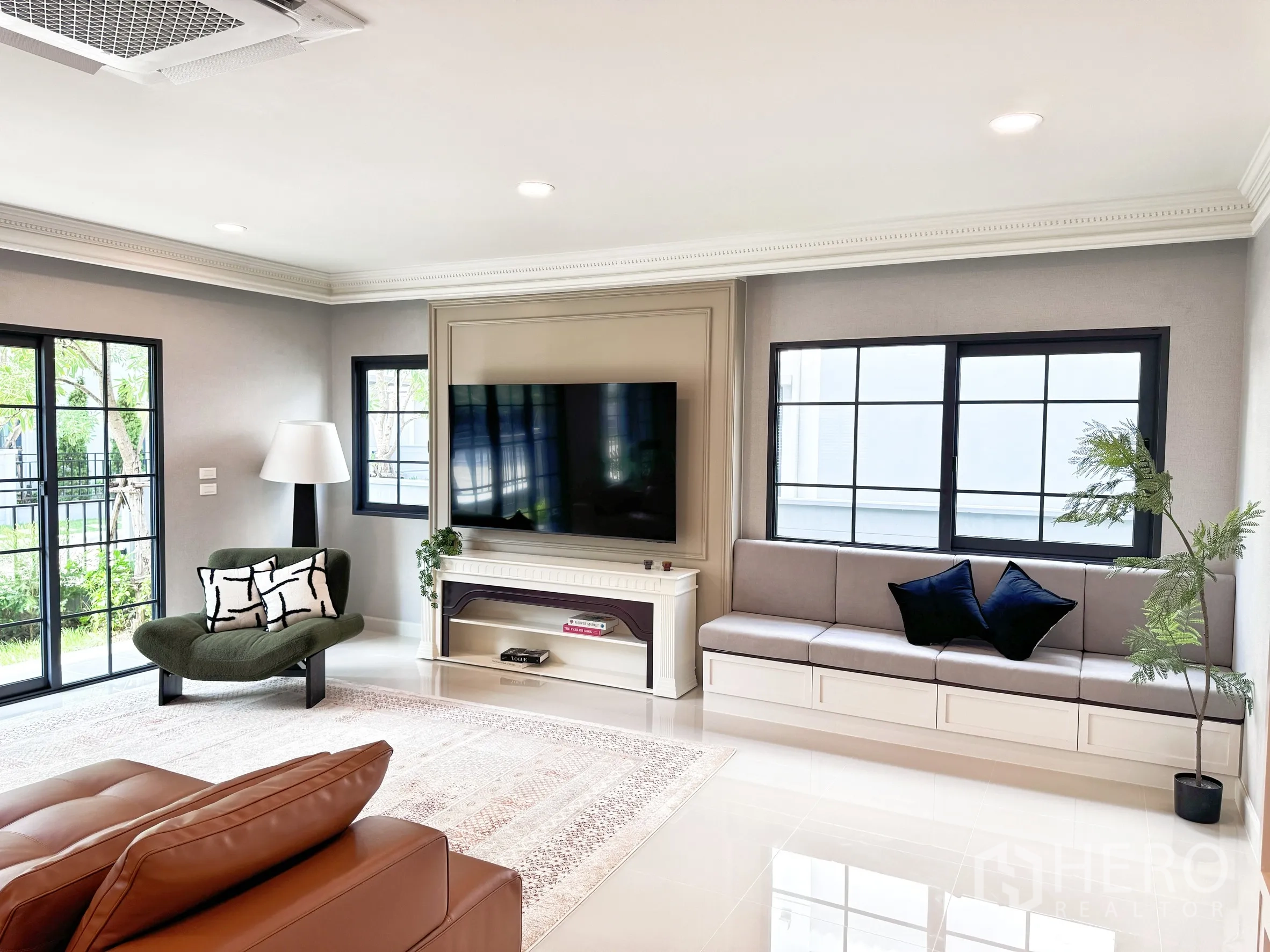 Detached House for rent in Bang Phli, Samut Prakan - TV wall with built-in bench seating, green armchair, and wide windows facing a small garden.