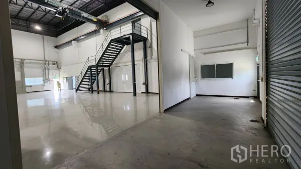 Factory for sale in Bang Bo, Samut Prakan - Polished epoxy production hall with mezzanine stairs and roller shutter.