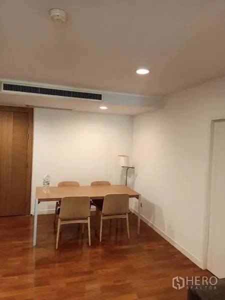Condominium for rent in Pathum Wan, Bangkok - Minimal dining corner with wooden table and four chairs under recessed lighting on hardwood flooring.