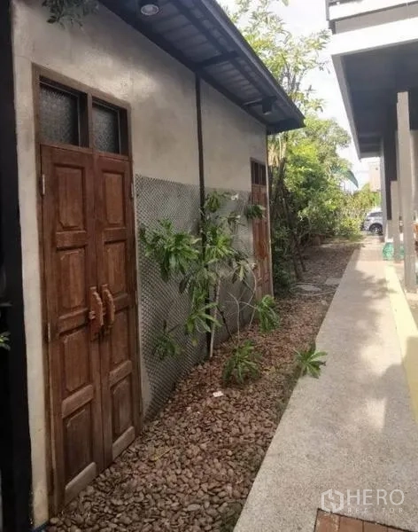 独立式住宅 出售在Pak Kret, Nonthaburi - 侧院步道铺卵石，复古木门与绿化。