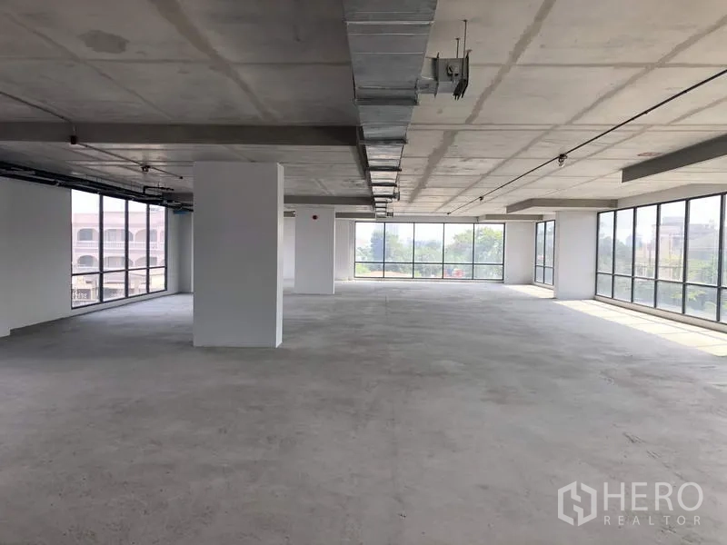 办公空间 出租在Suan Luang, Bangkok - 宽敞转角办公区，环绕玻璃、混凝土天花与结构立柱，适合自由布局。