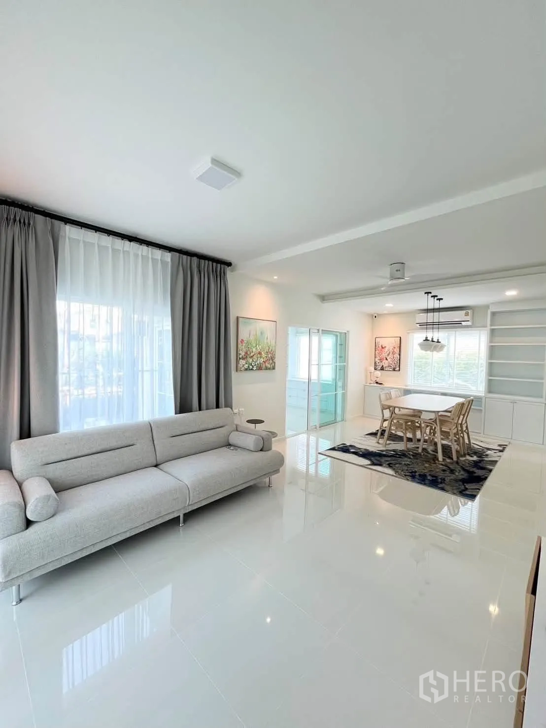 Detached House for rent in Bang Phli, Samut Prakan - Open-plan living and dining with gray sofa, dining set, and glass doors.