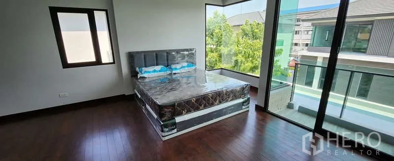 Detached House for rent in Wang Thonglang, Bangkok - Corner bedroom with wood floors and full-height glass walls offering neighborhood views.