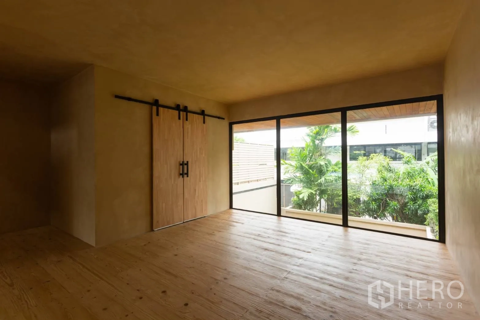 Home Office for rent in Watthana, Bangkok - Private room with barn‑style sliding doors and greenery view through large windows.