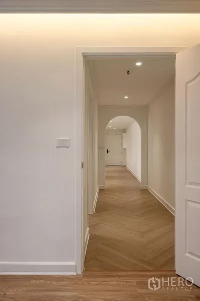 Condominium for sale in Watthana, Bangkok - Bright hallway with chevron wood flooring, recessed lights and an arched doorway.