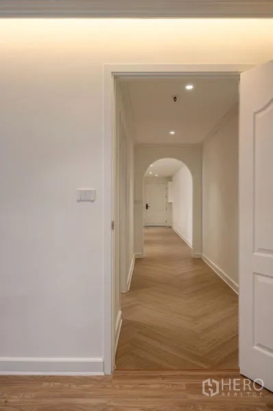 Condominium for sale in Watthana, Bangkok - Bright hallway with chevron wood flooring, recessed lights and an arched doorway.