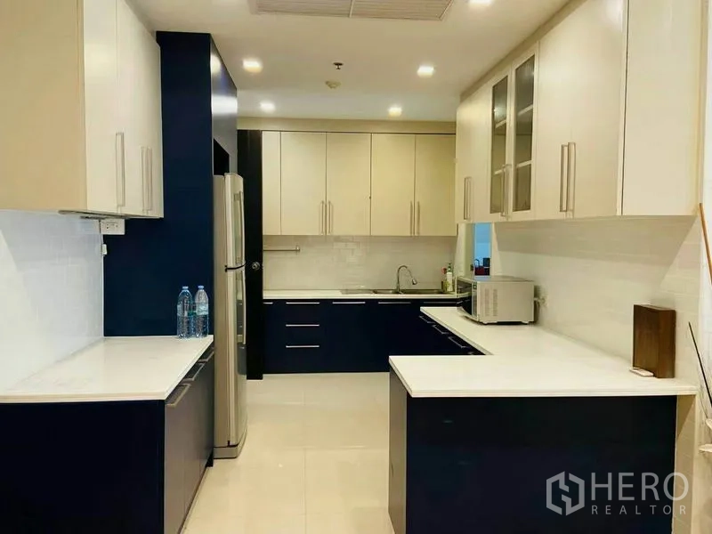Condominium for rent in Watthana, Bangkok - Full kitchen showcasing ample cabinetry, stainless refrigerator, and stone counters.