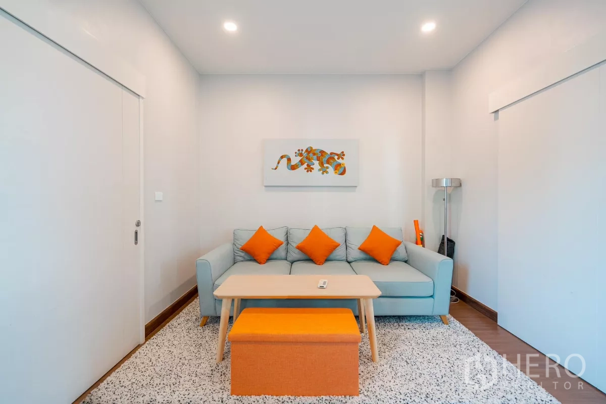 บ้าน ขายในSaphan Sung, Bangkok - ห้องอเนกประสงค์บรรยากาศอบอุ่น โซฟาและหมอนสีส้มพร้อมภาพตกแต่ง