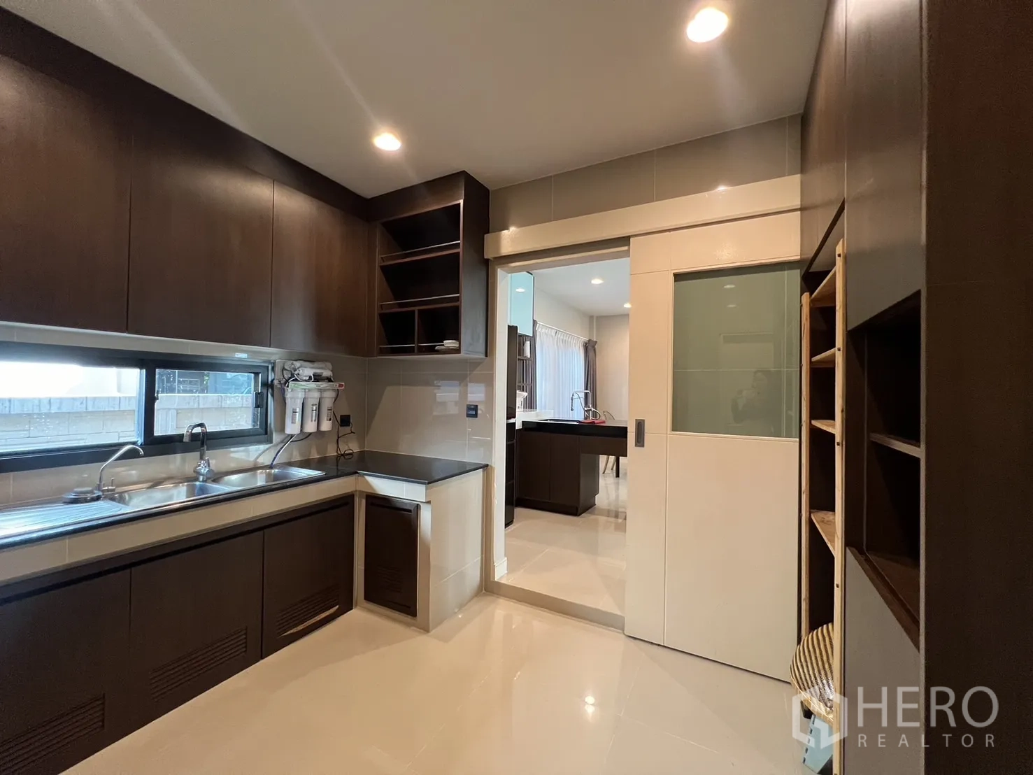 Detached House for rent or sale in Bang Kapi, Bangkok - Kitchen with long counter, double sink and sliding door to dining area.