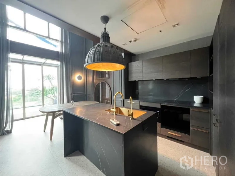 公寓 出售在Khlong Toei, Bangkok - 现代深色厨房，带大理石中岛、金色龙头与落地窗。