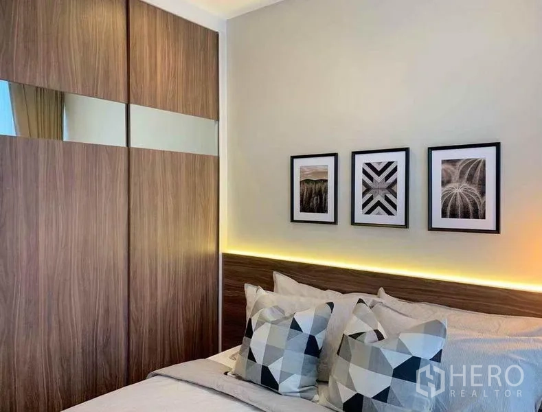 Condominium for sale in Ratchathewi, Bangkok - Bedroom with mirrored sliding wardrobe, geometric pillows and soft lighting.